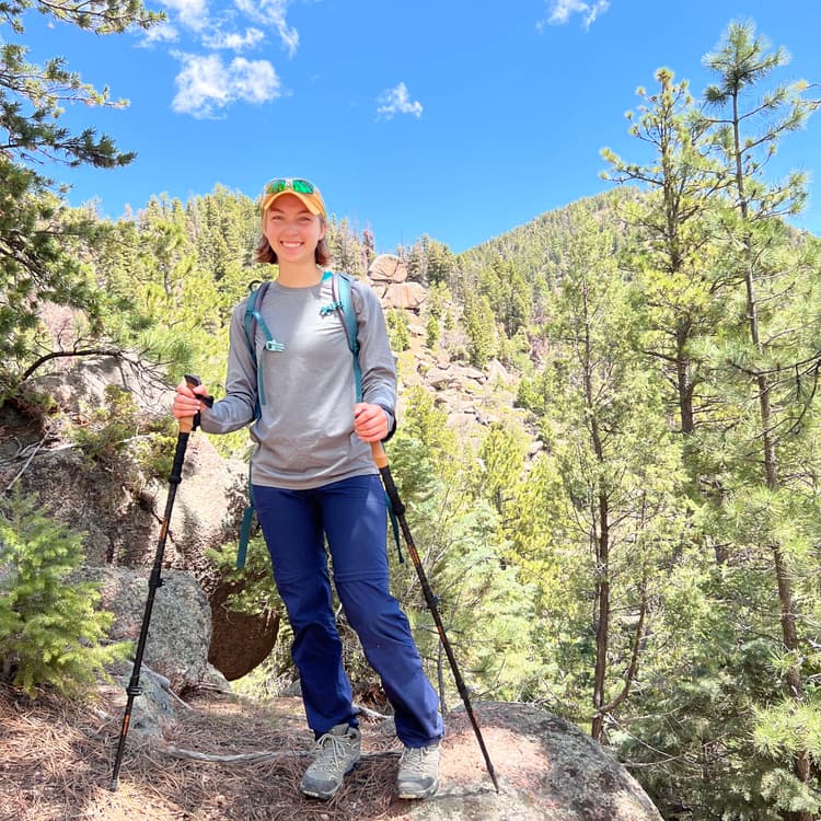 Picture of me in hiking gear with green trees and a blue sky in the background